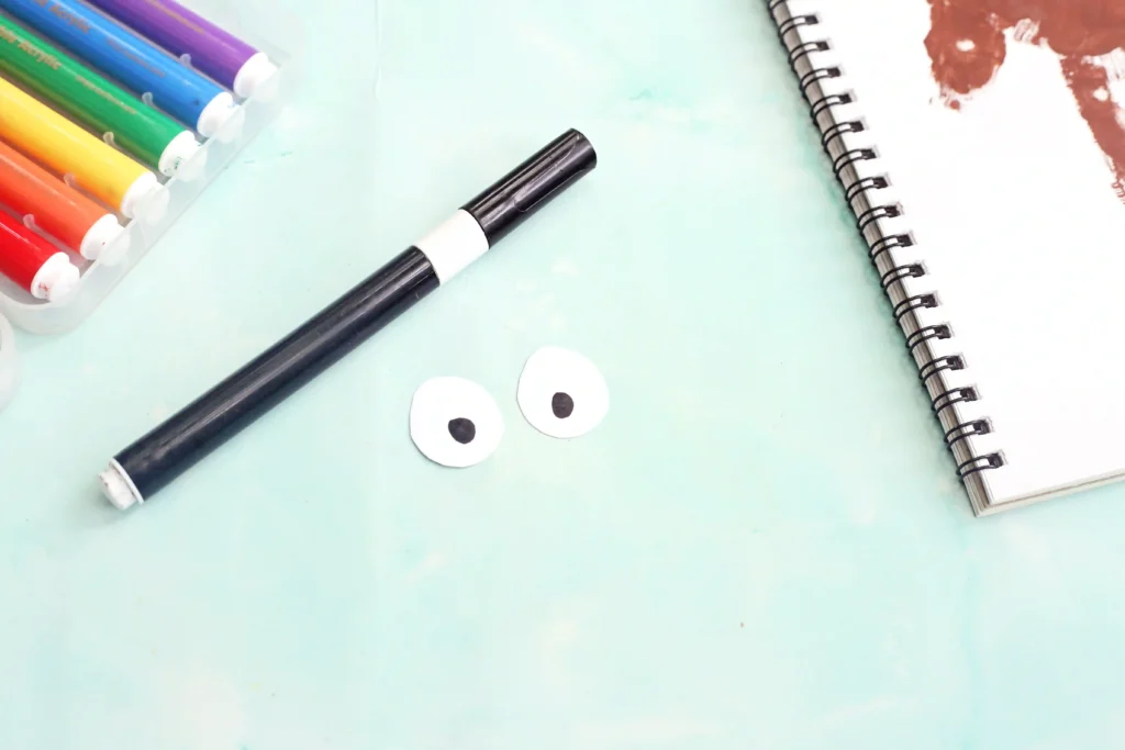 white paper cut into two circles with black dots to look like eyes