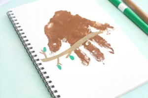Spiral-bound notebook page with brown paint handprint with a branch drawn on