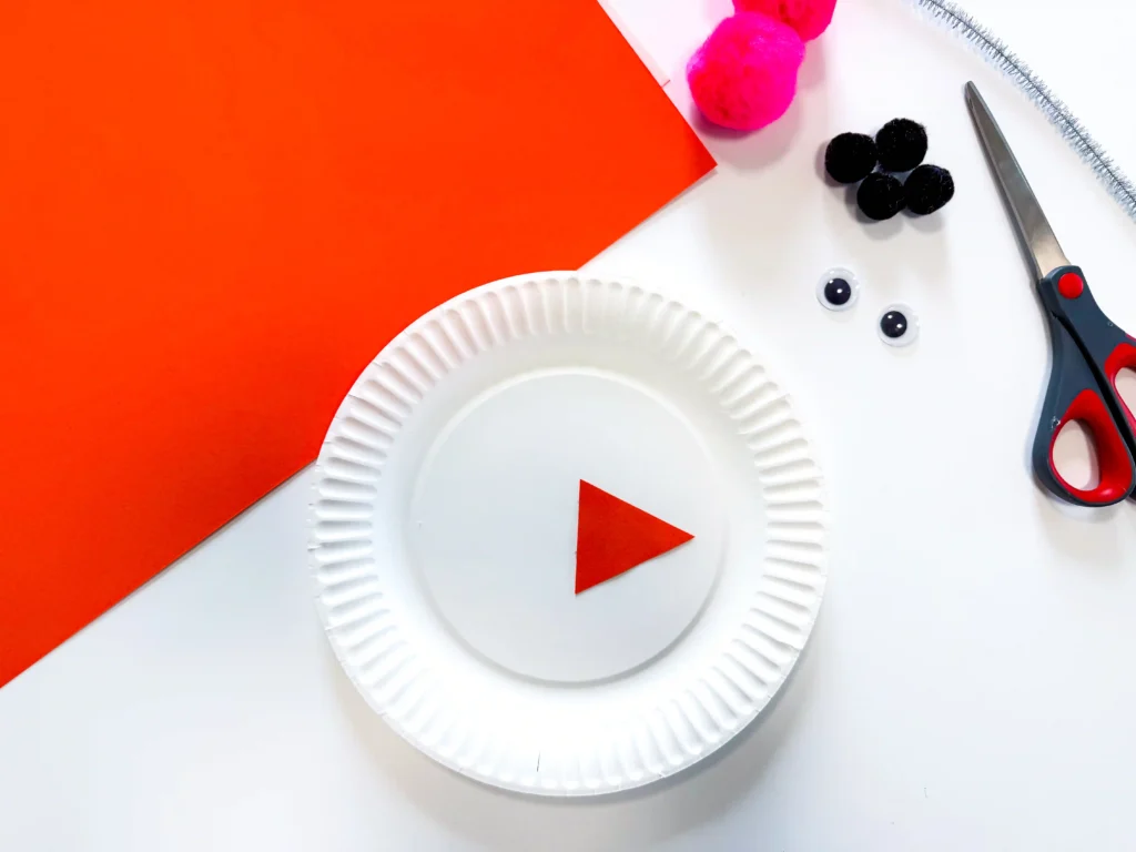 Paper Plate Snowman Craft - Cultivating Brilliant Minds a paper plate with an orange triangle glued on
