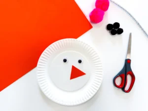 paper plate with googly eyes and a triangle orange nose