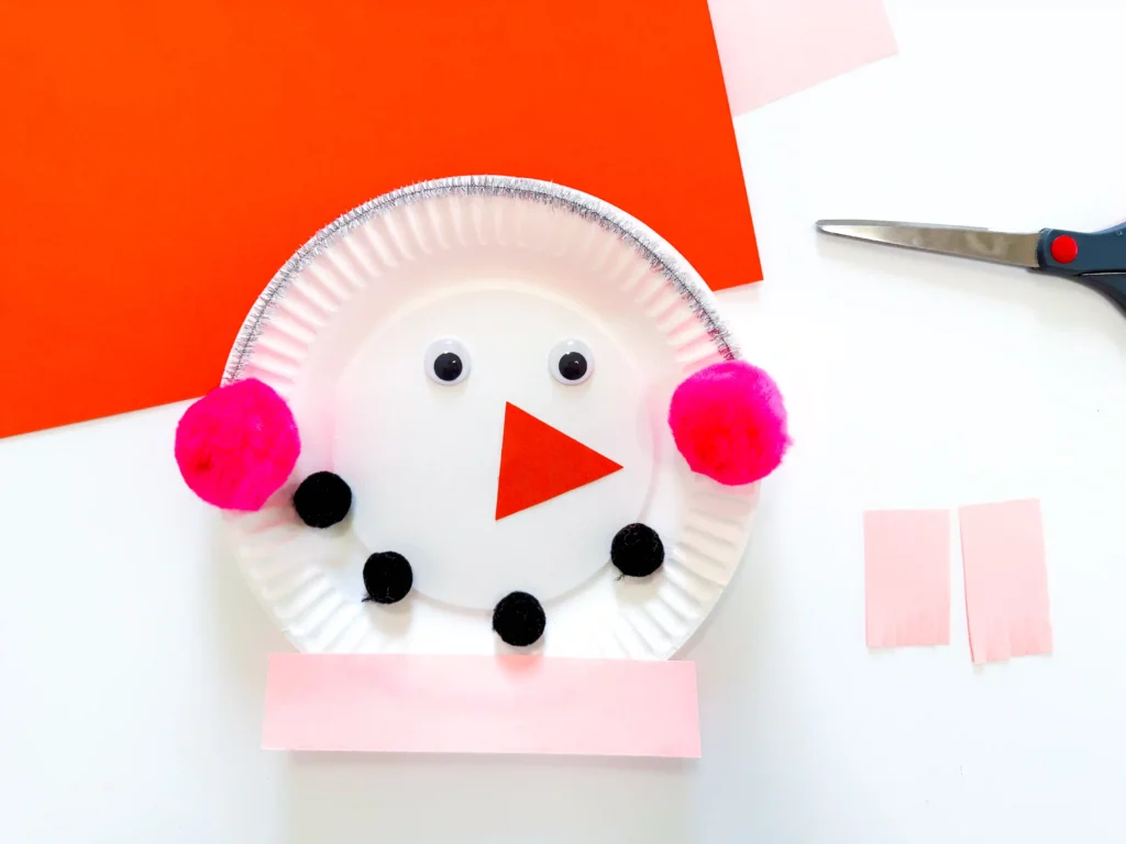 Paper Plate Snowman Craft - Cultivating Brilliant Minds paper plate snowman craft of a paper plate decorated to look like a snowman with earmuffs and a scarf