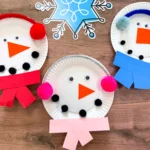paper plates decorated to look like snowmen with earmuffs and scarves