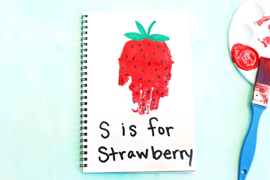 a red handprint decorated to look like a strawberry with the words "s is for strawberry"
