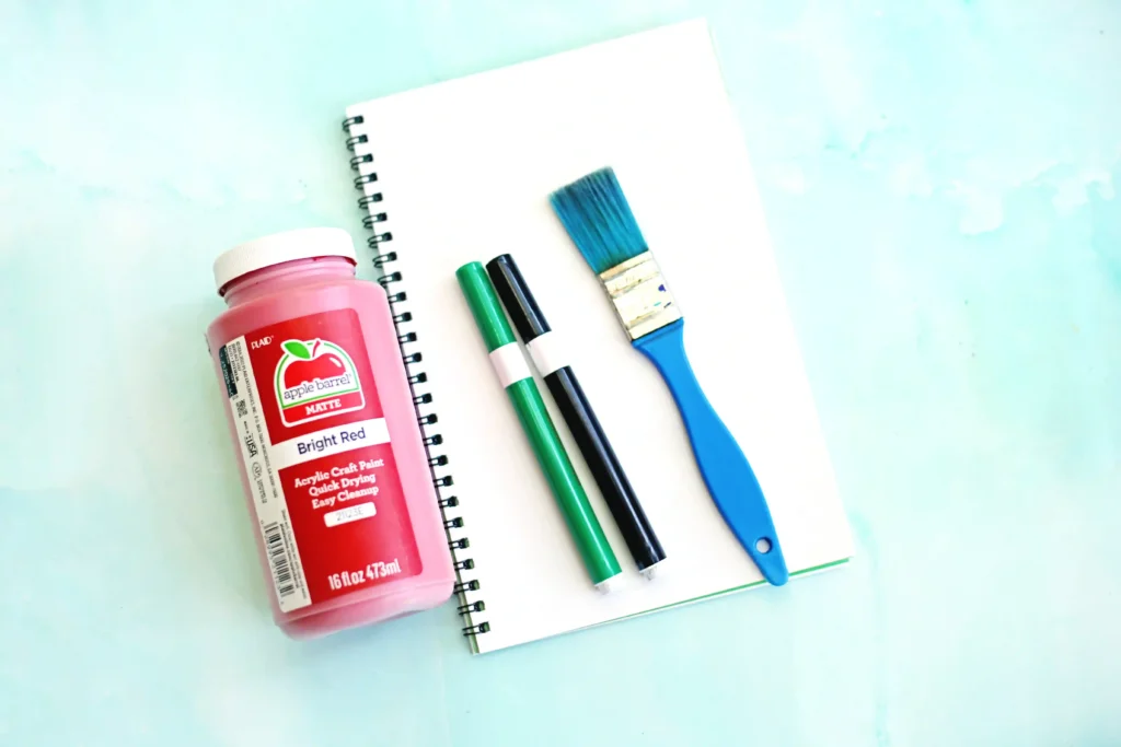 supplies for the letter s handprint craft: notebook paper, red paint, green and black marker, and paintbrush