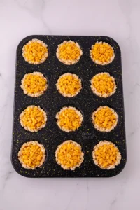 Muffin tin with twelve cups of rice krispies cereal batter