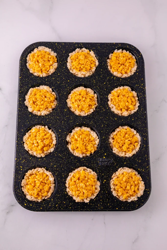Muffin tin with twelve cups of rice krispies cereal batter