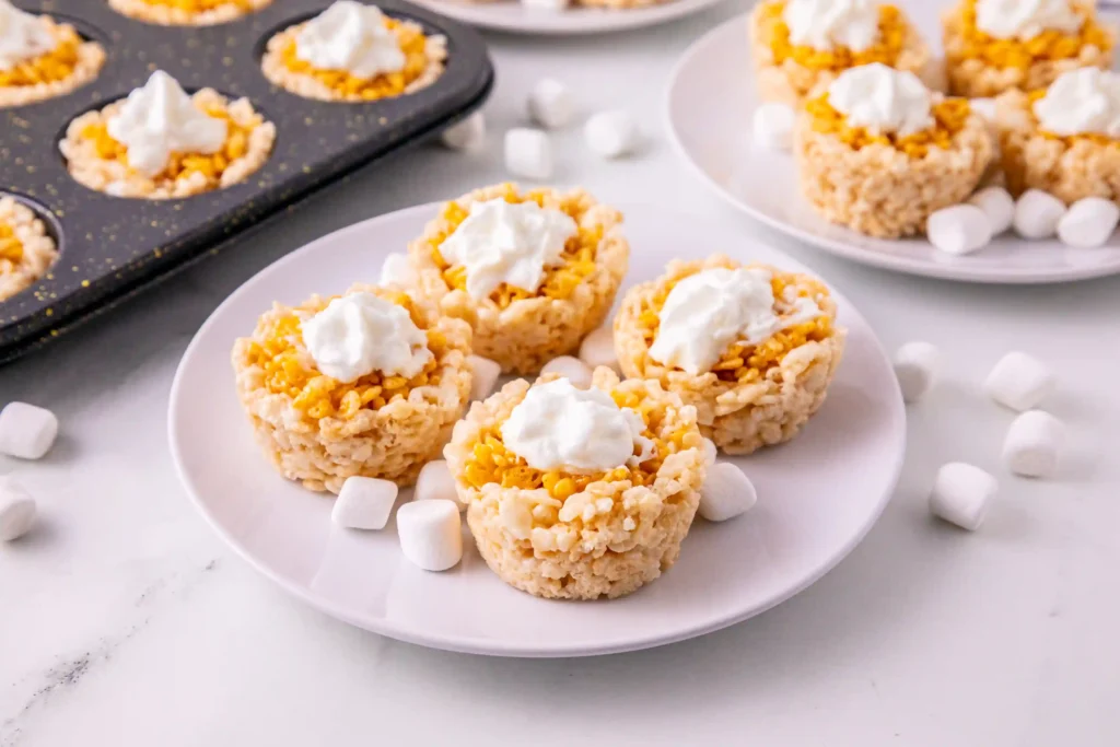 Mini Pumpkin Pie Rice Krispie Treats with whipped cream on top on a white plate