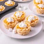 Mini Pumpkin Pie Rice Krispies with whipped cream on top on a white plate