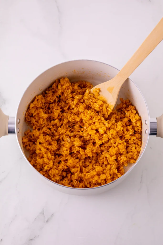 orange pumpkin rice krispie treat cereal in a pot with a wooden spoon