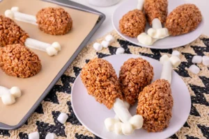 Rice Krispie Turkey Legs on a white plate with other rice krispie turkey legs in the background