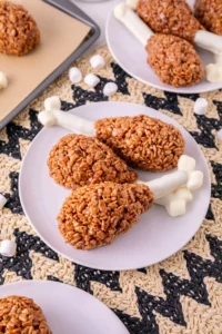 Rice Krispie Turkey Legs on a white plate with other rice krispie turkey legs in the background