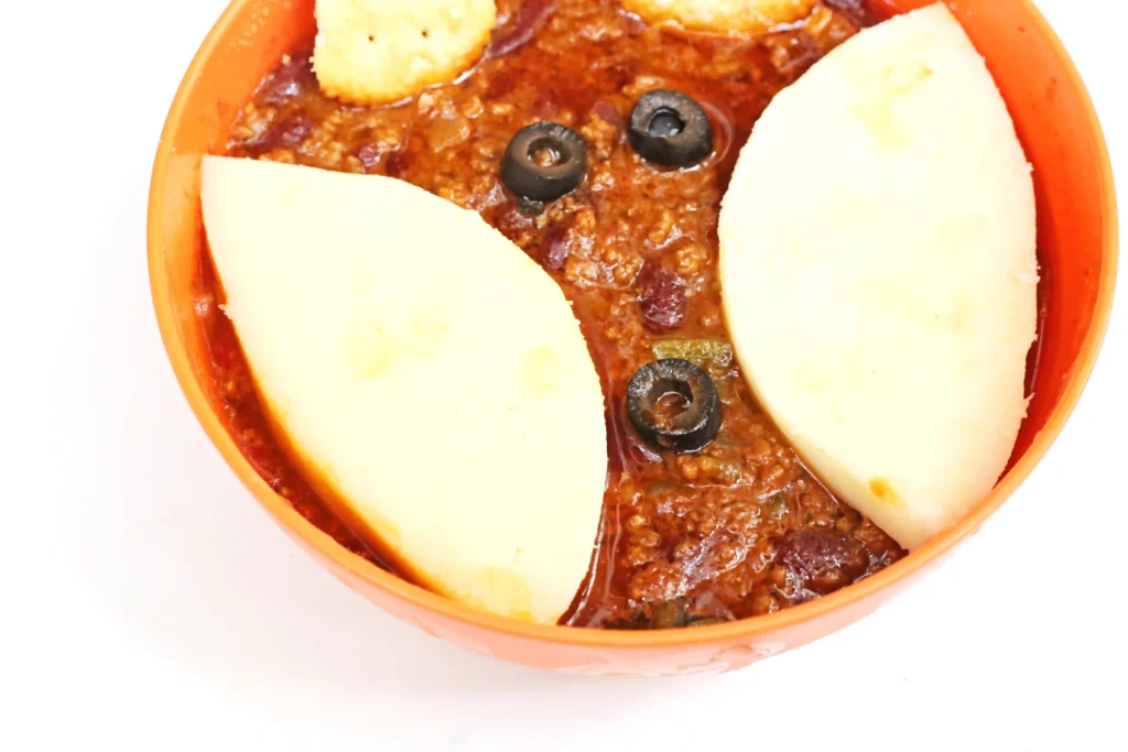 fox chili in a bowl - chili with olives, crackers, and cheese slices on top to look like a fox
