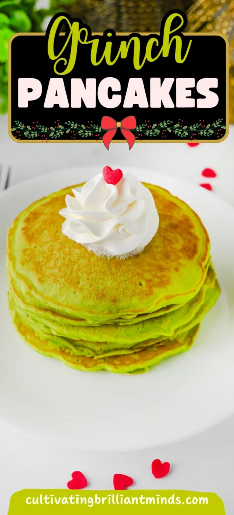 green panckaes with whipped cream and heart sprinkles on a white plate next to a grinch napkin