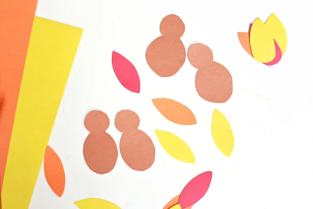 Abstract paper with orange, red, and yellow shapes on a white background resembling feathers and turkeys