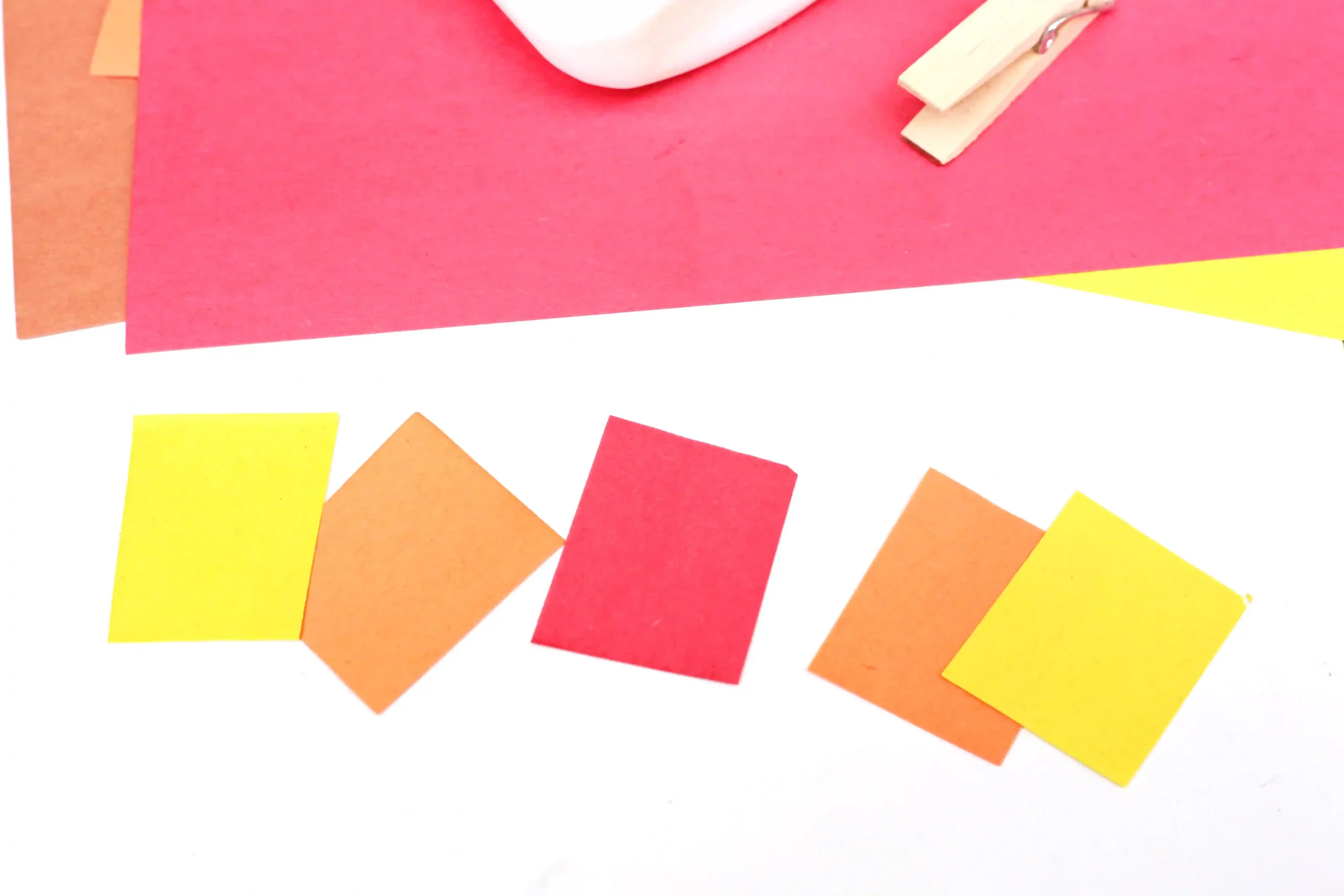 Colorful paper pieces (red, orange, yellow) scattered on a white background.