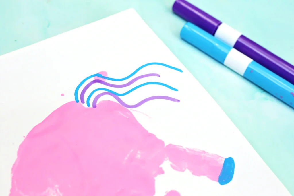 Colorful desk scene with a spiral notebook, a handprint unicorn on the page