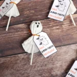 Halloween ghost lollipops with tags reading 'Have a boo-tastic Halloween' on a rustic wooden surface.