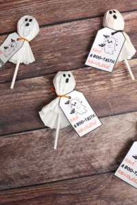 Halloween ghost lollipops with tags reading 'Have a boo-tastic Halloween' on a rustic wooden surface.