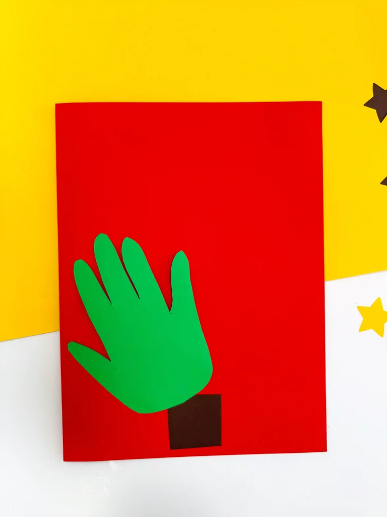 red construction paper with a brown tree trunk and green handprint