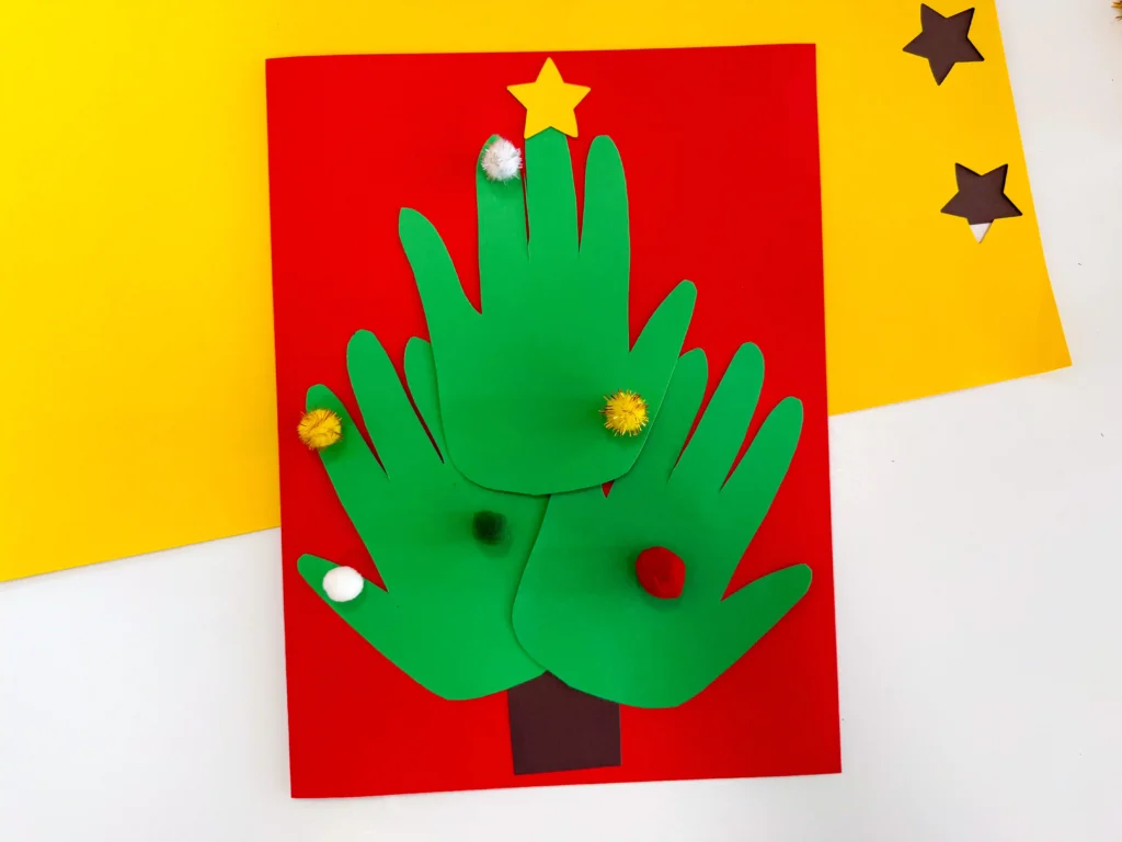 a Handprint Tree Christmas Card made of construction paper handprints and pom poms