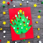 a Handprint Tree Christmas Card made of construction paper handprints and pom poms