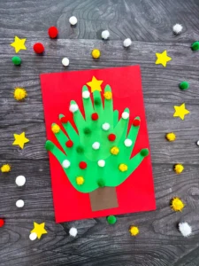 a Handprint Tree Christmas Card made of construction paper handprints and pom poms
