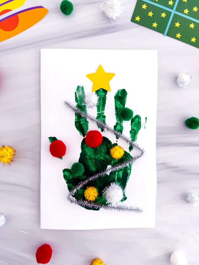 a Handprint Christmas Tree Card made with a green handprint, pipe cleaner, and pom poms