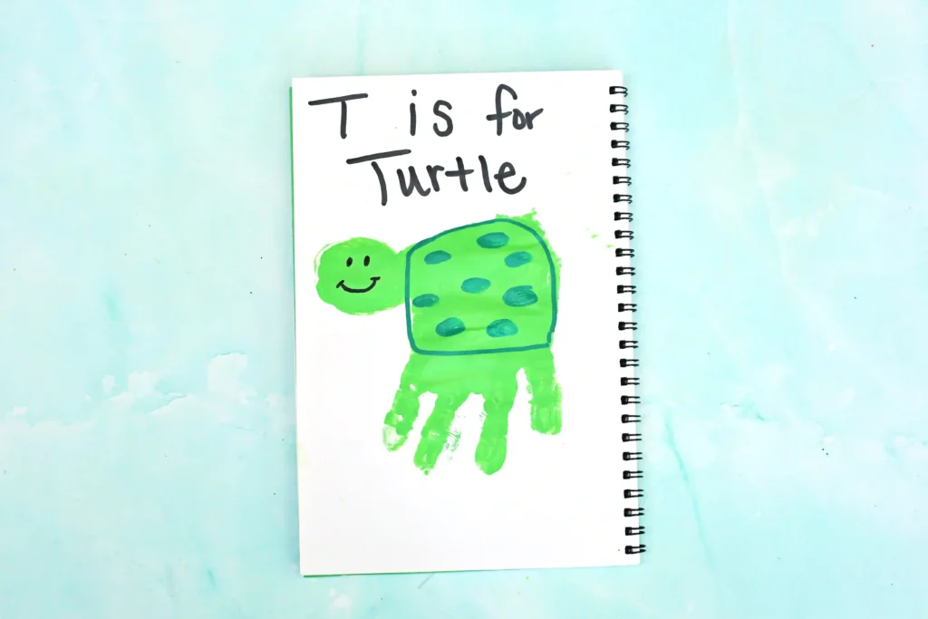 a Letter T Handprint Craft of a green handprint turned into a turtle with the words "T is for turtle" written above it.