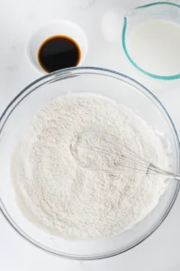 flour, sugar, baking powder, baking soda, and salt in a glass bowl with a whisk