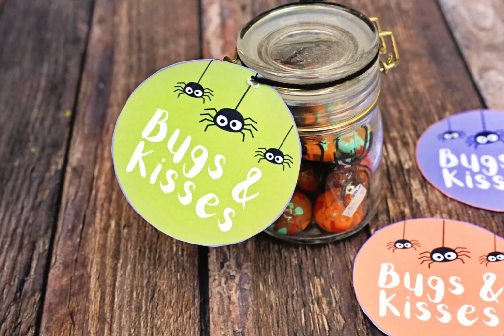 a jar with toys spiders and candy with a tag that says bugs and kisses