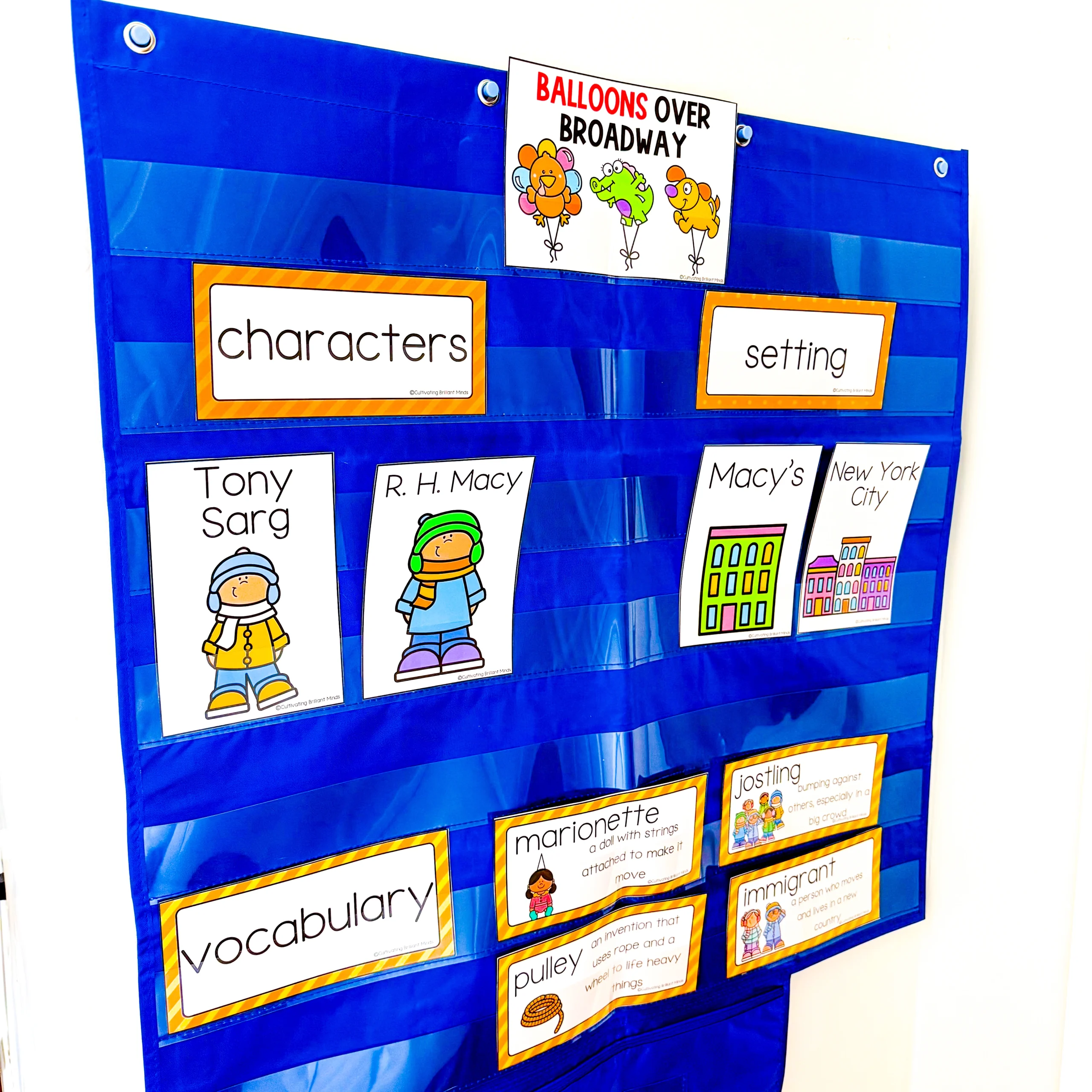 Blue fabric pocket-chart display with orange-bordered vocabulary cards and cartoon characters, likely a classroom learning board.