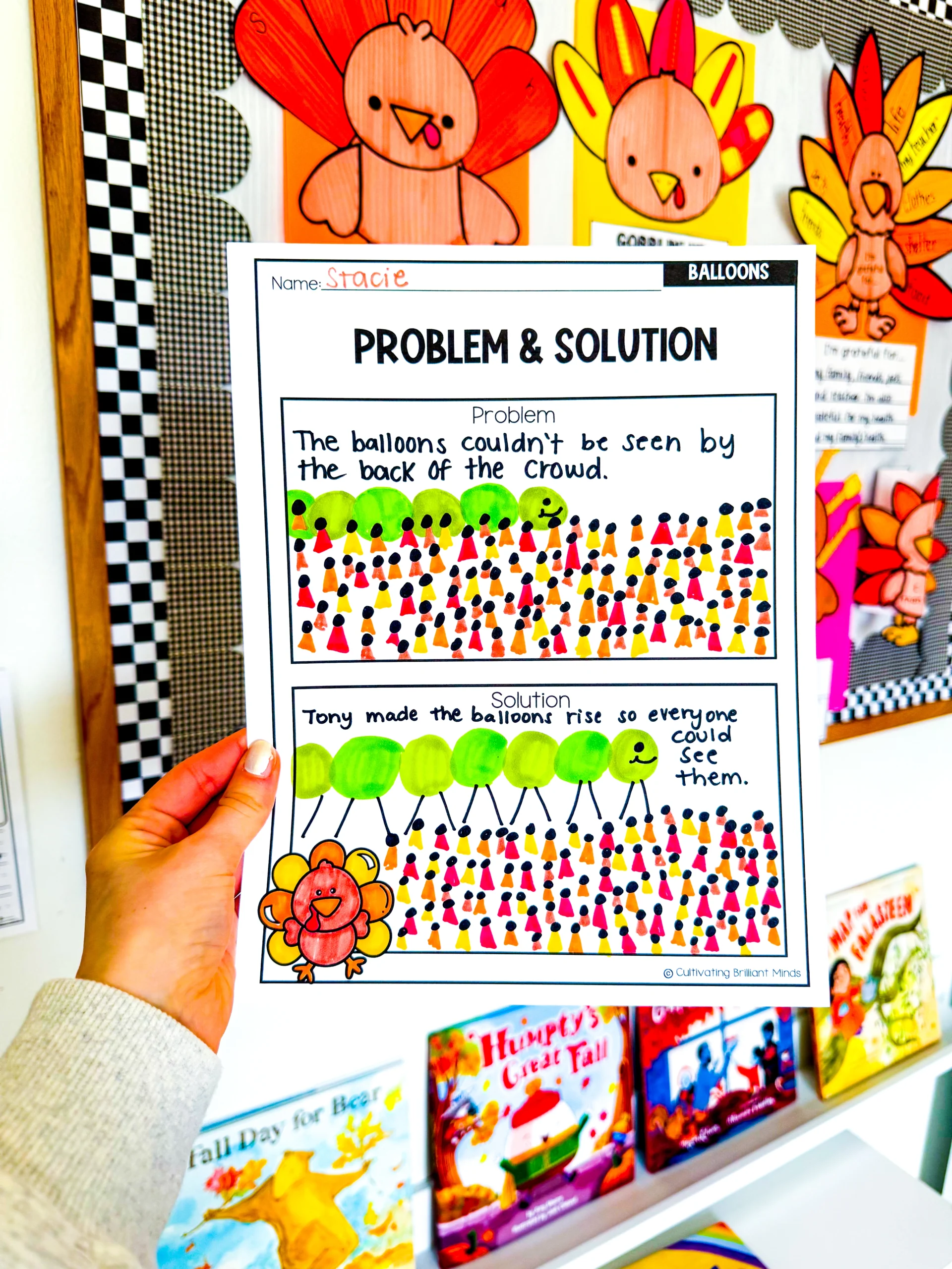 Person holding a worksheet titled 'Problem & Solution' about balloons, with a handwritten name and colorful drawings in the margins.