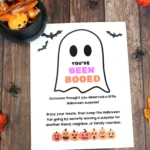 Halloween-themed flyer with a ghost outline and the phrase 'YOU'VE BEEN BOOED' in colorful letters, surrounded by pumpkins and bats on a wooden surface.