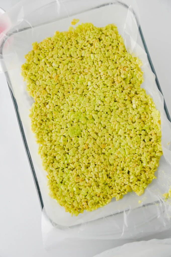 Parchment-lined baking sheet spread with a layer of green rice krispie treats